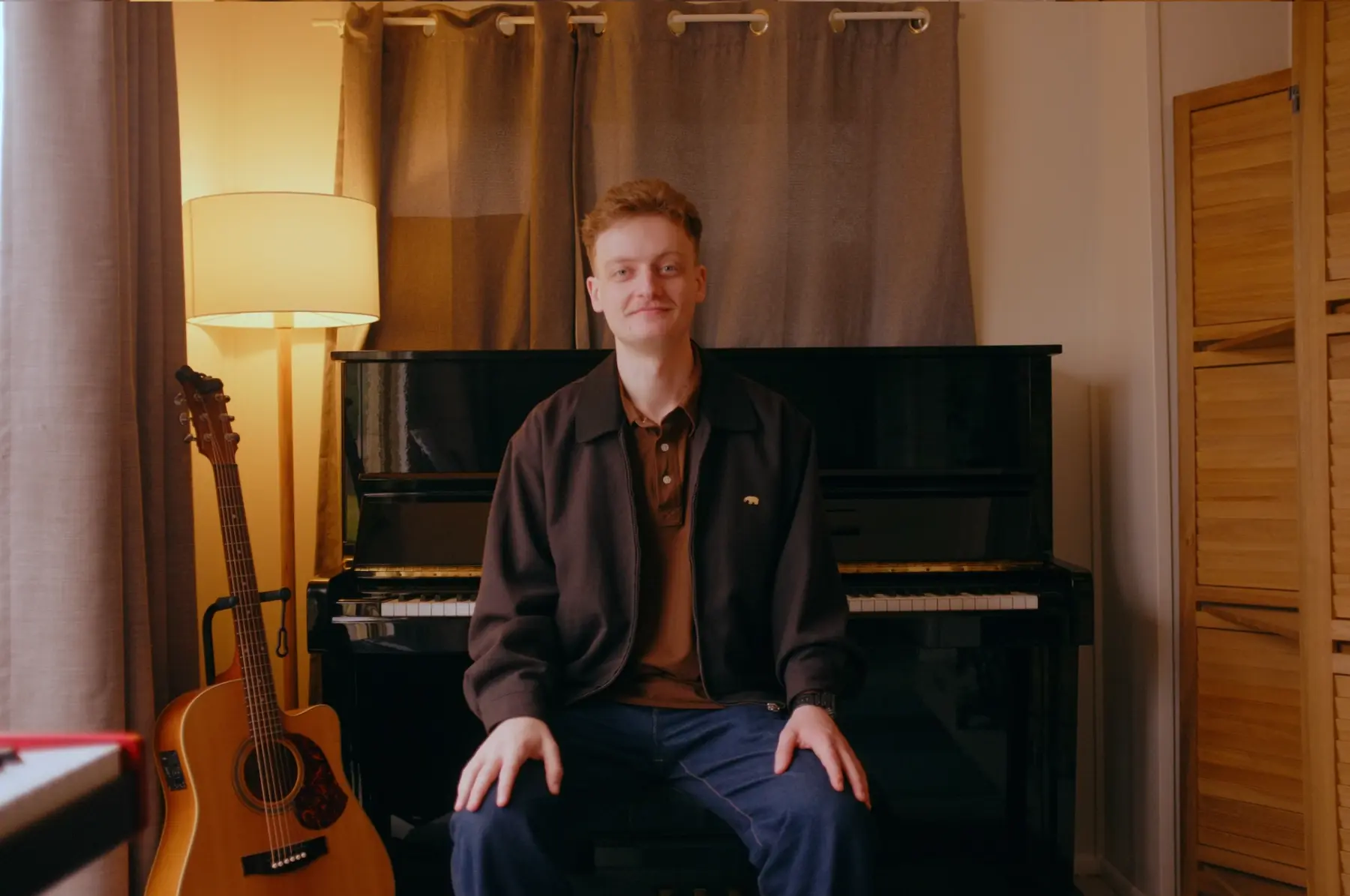 Reuben seated beside the upright piano in his home studio